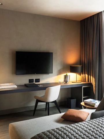 Modernes Hotelzimmer mit Schreibtisch, Fernseher und gemütlicher Beleuchtung