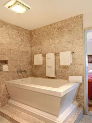 Offenes Badezimmer mit Badewanne und Blick ins Schlafzimmer