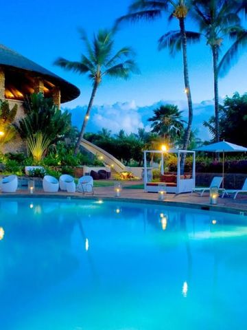 Abendansicht eines beleuchteten Pools mit Palmen