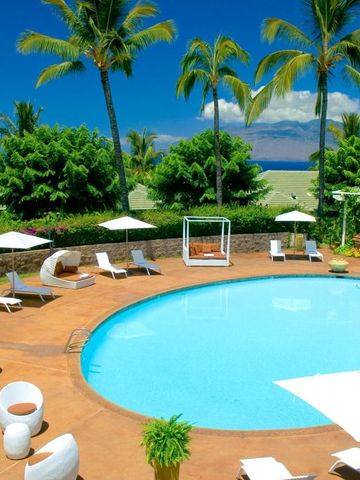 Tagesansicht eines Pools mit Liegestühlen und Palmen