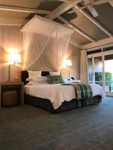 Geräumiges Schlafzimmer mit Himmelbett und großen Fenstern