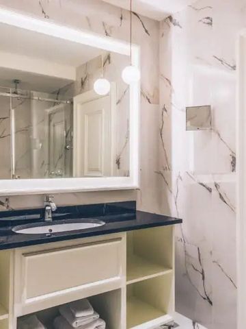 Elegantes Badezimmer mit Marmorwänden und beleuchtetem Spiegel