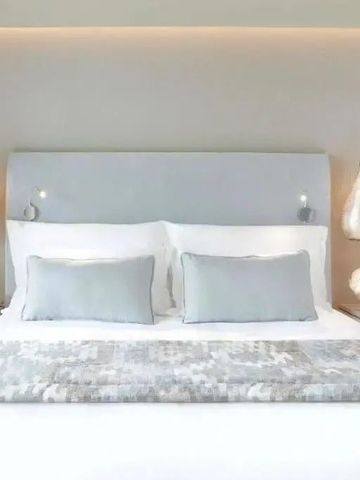 Detailansicht eines stilvollen Bettes mit weichen Kissen und hängenden Lampen