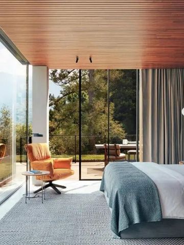 Elegantes Schlafzimmer mit Glasfront und Blick auf Natur