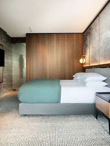 Modernes Hotelzimmer mit Holzwänden, großem Bett und stilvoller Beleuchtung