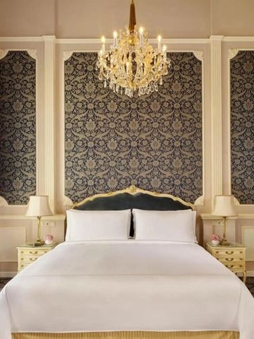 Geräumiges Schlafzimmer mit detaillierter Tapete und edlem Kronleuchter.