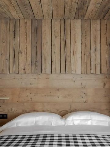 Gemütliches Schlafzimmer mit Holzverkleidung und kariertem Bettüberwurf