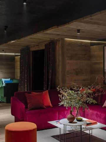 Einladende Lounge mit rotem Sofa, Kunstwerken und eleganter Beleuchtung.