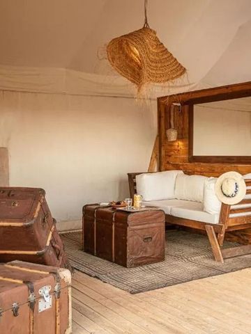 Einladende Sitzecke mit Sofa und rustikalem Koffer im Zelt des Inara Camp.