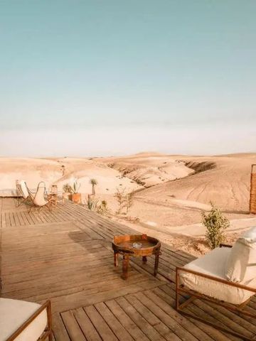 Holzterrasse mit Sitzgelegenheiten und Ausblick auf die Wüste