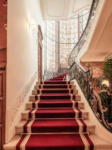 Elegante Treppe mit rotem Teppich und verziertem Geländer