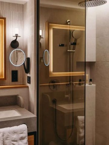 Elegantes Badezimmer mit moderner Dusche und stilvollem Spiegel im Hotelzimmer