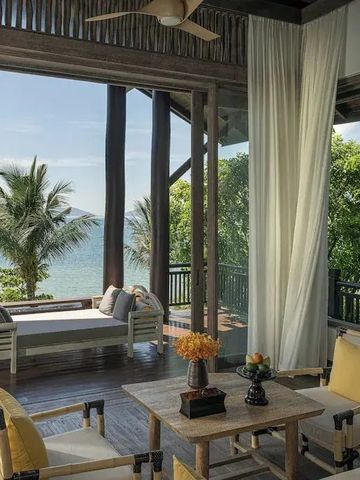 Privater Balkon mit Sitzbereich und Aussicht auf Palmen und das Meer.