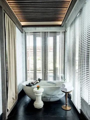 Moderne Badewanne mit eleganten Vorhängen und Fenstern in luxuriösem Badezimmer.