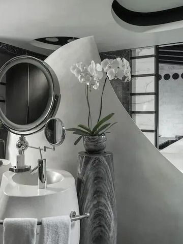 Modernes Badezimmer mit skulpturalem Waschbecken und dekorativen Pflanzen.