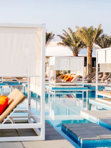 Sonnenliegen am Pool mit Palmen im Hintergrund im InterContinental Fujairah Resort