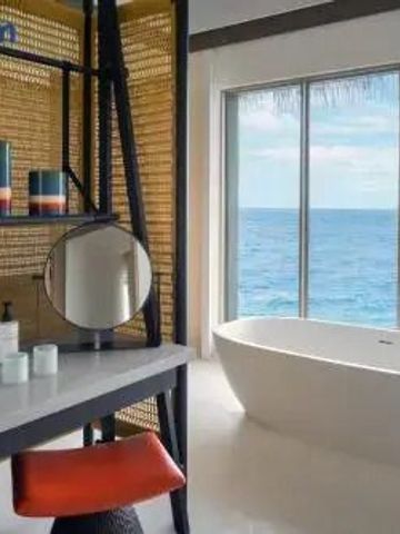 Luxuriöses Badezimmer mit freistehender Badewanne und Blick auf das Meer.