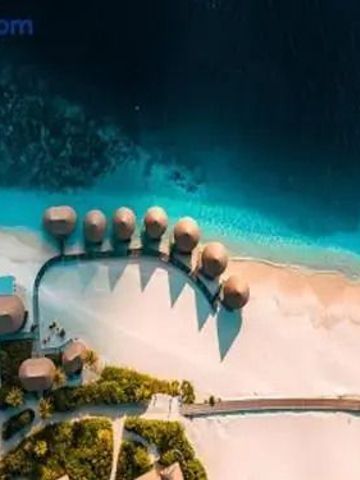 Luftaufnahme der Resortvillen auf dem Wasser neben einem weißen Sandstrand