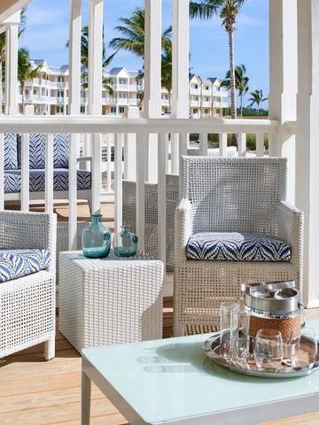 Terrasse mit weißen Korbmöbeln und direktem Zugang zum Sandstrand.