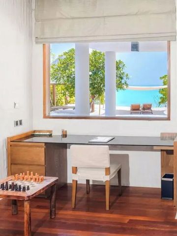 Arbeitsbereich mit Schreibtisch vor einem Fenster mit Meerblick und Schachspiel auf Tisch