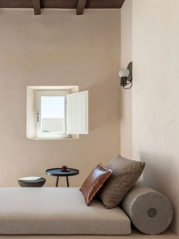 Gemütlicher Wohnbereich mit Sitzgelegenheit und kleinem Fenster im mediterranen Stil.