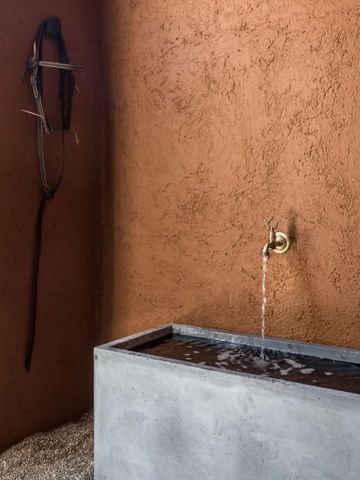 Detailaufnahme einer stilvollen Wassersoße an einer strukturierten Terrakotta-Wand.