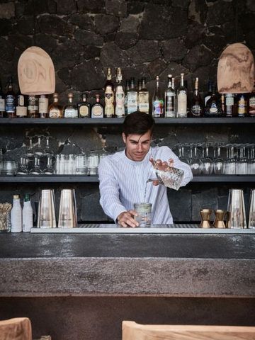 Barkeeper mixt Getränk hinter der stilvollen Hotelbar mit Steinwand.