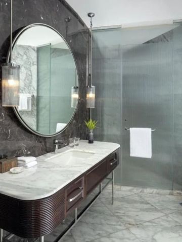 Moderne Badezimmerausstattung mit Marmordesign und runder Spiegelbeleuchtung.