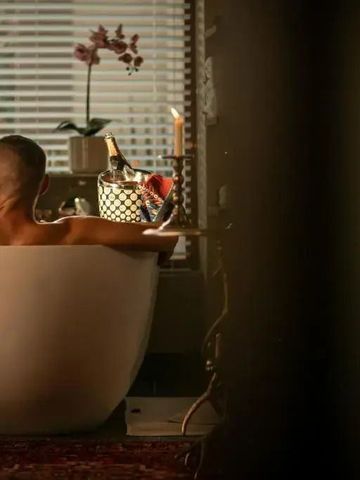 Luxuriöses Bad mit Mann in freistehender Wanne und Pflanzen