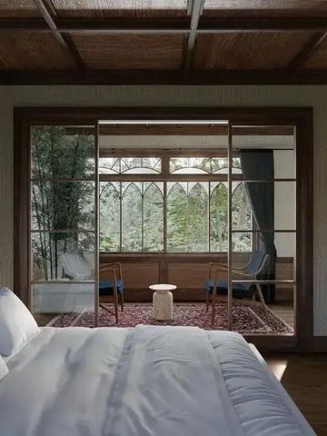 Geräumiges Schlafzimmer mit Blick auf einen begrünten Balkon durch große Fenster.
