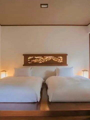 Zwei Doppelbetten in einem japanischen Schlafzimmer mit dezenten Lampen.