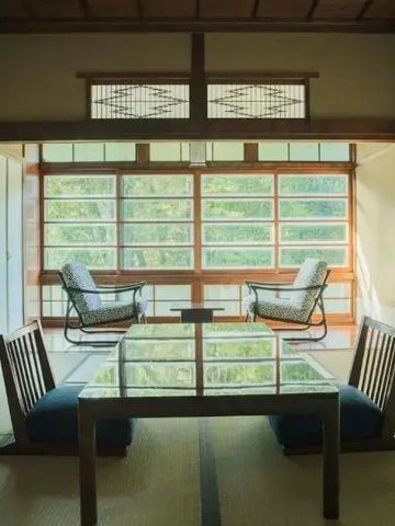 Sitzbereich mit Tatami-Boden und großen Fenstern mit Blick auf die Natur
