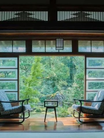 Zwei Sessel vor großen Fenstern mit atemberaubendem Gartenblick