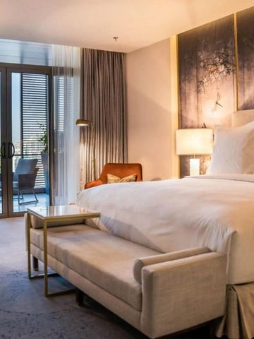 Luxuriöses Schlafzimmer mit großzügigem Bett und Zugang zum Balkon mit Stadtblick