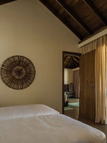 Schlafzimmer mit zwei Betten und Holzdecke in tropischem Design