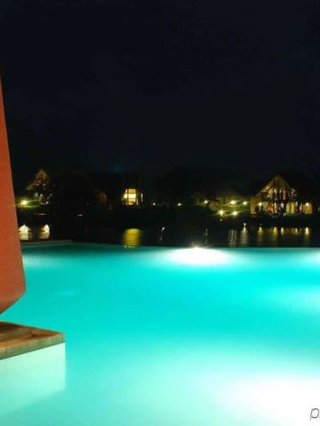 Nachtaufnahme eines beleuchteten Pools mit Aussicht auf Wasser und Häuser