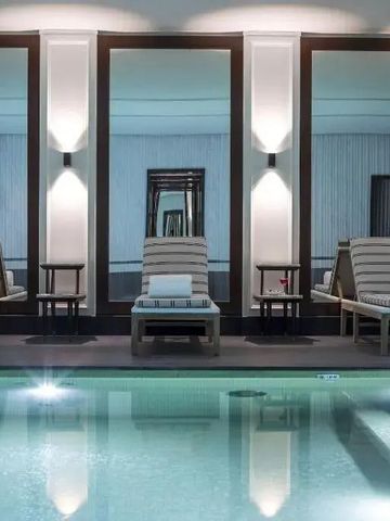 Innenpool mit eleganten Liegen und Spiegeln im J.K. Place Paris
