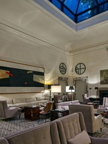 Elegante Lobby mit Kunstwerken und gemütlichen Sitzbereichen unter Glasdach