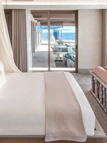 Elegantes Schlafzimmer mit Blick durch große Fenster auf das Meer