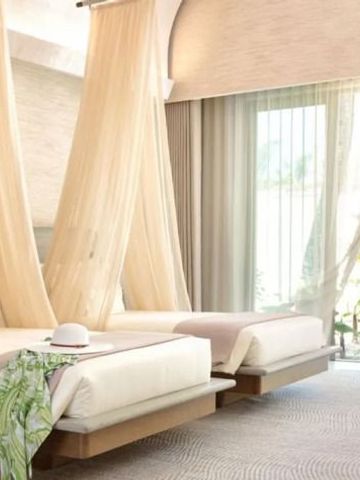 Zwei Himmelbetten in einem hellen, luftigem Raum mit Gartenblick