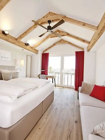 Helles Hotelzimmer mit Holzbalkendecke Doppelbett und rotem Vorhang