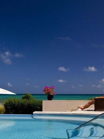 Infinity-Pool mit Blick auf das Meer und einen Sonnenbadenden unter Sonnenschirm