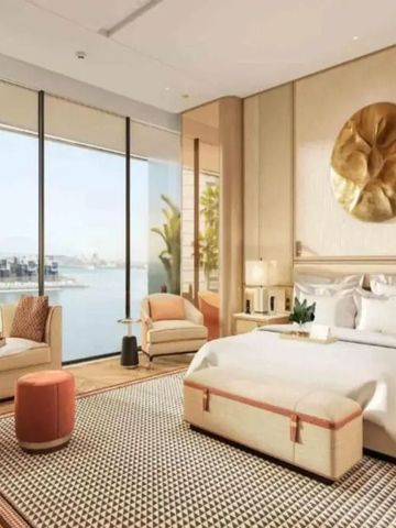 Luxuriöses Hotelzimmer mit großem Bett und Meerblick durch bodentiefe Fenster.