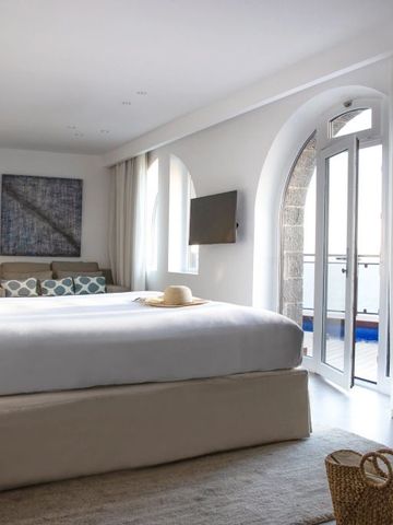 Helles Hotelzimmer mit Doppelbett und Zugang zu einem Balkon.