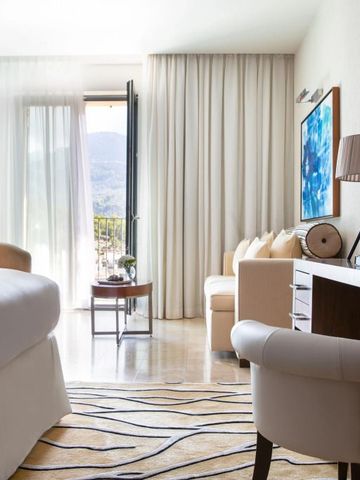 Zimmer mit großen Fenstern, Sitzbereich und eleganter Einrichtung.