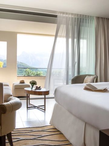 Elegantes Hotelzimmer mit großem Bett und Panoramafenster mit Bergblick