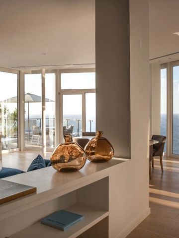 Helle Suite mit Blick auf das Meer durch große Glasfenster und eleganter Einrichtung