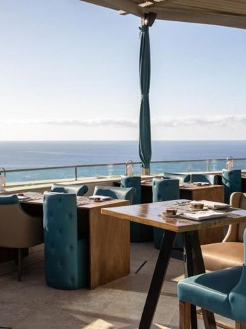 Terrassenrestaurant mit Polstermöbeln und weitem Blick über das Meer