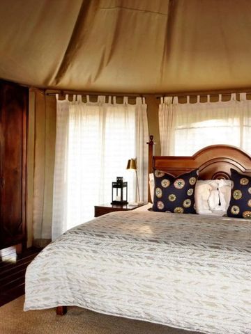 Elegantes Schlafzimmer mit Holzmöbeln und Himmelbett im Safaristil