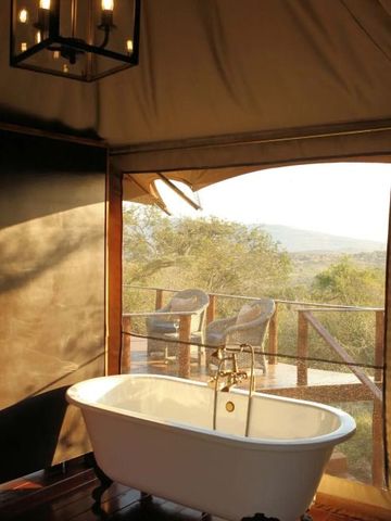 Freistehende Badewanne mit Blick auf die afrikanische Landschaft im luxuriösen Badezimmer